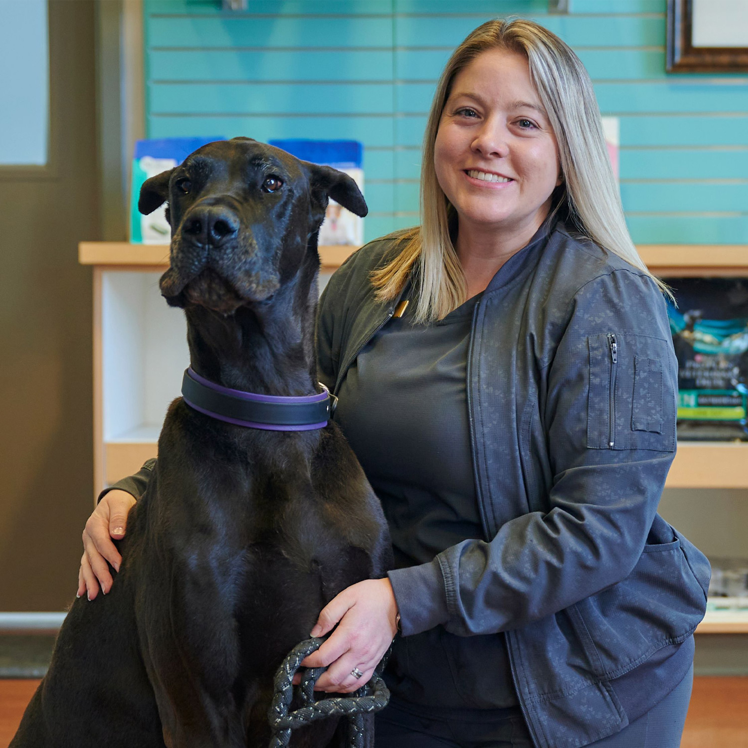 This image depicts a vet posing with a dog patient in a veterinary office.
